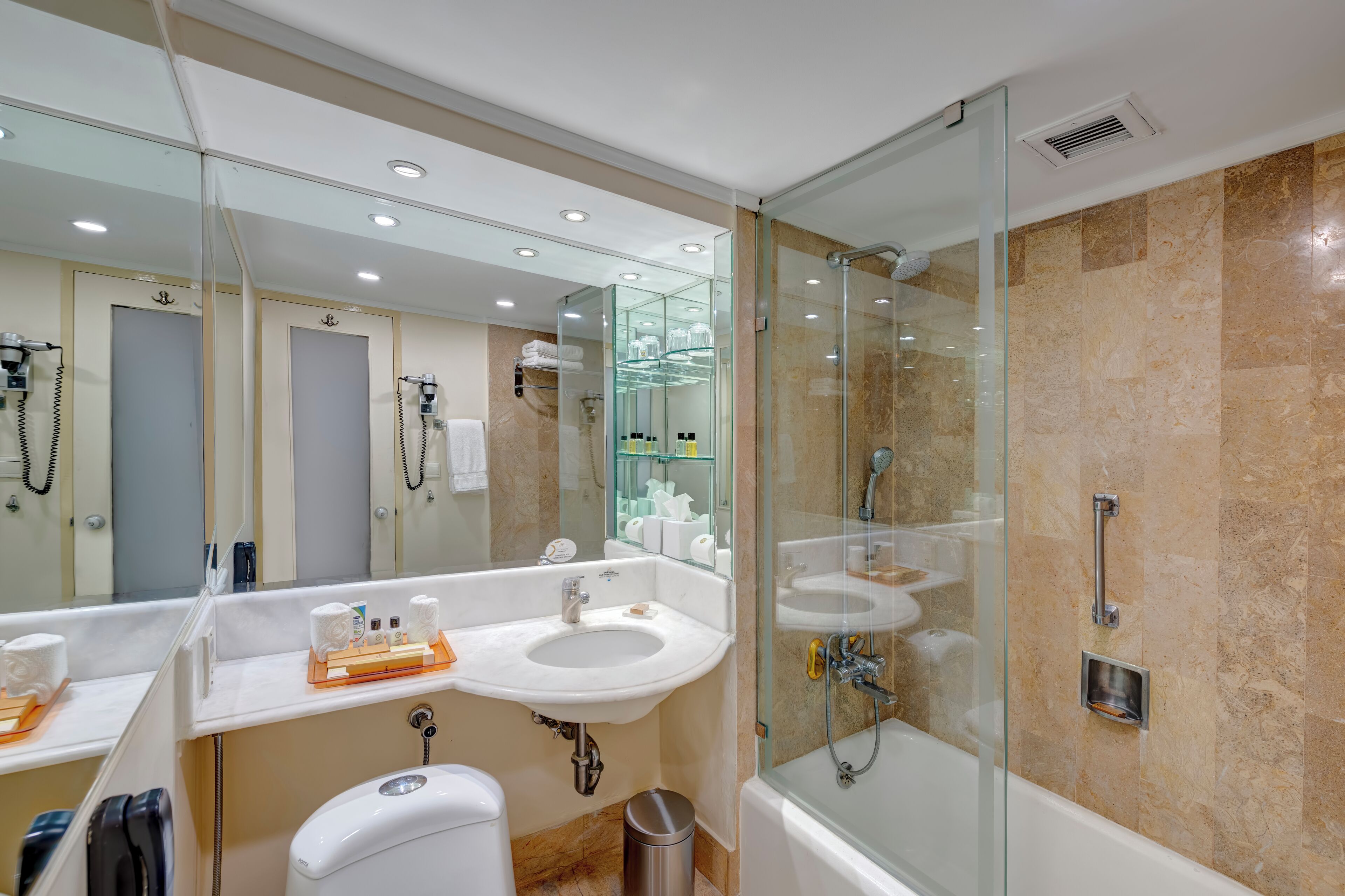 A modern bathroom with a glass-enclosed shower, a sink, and a toilet.