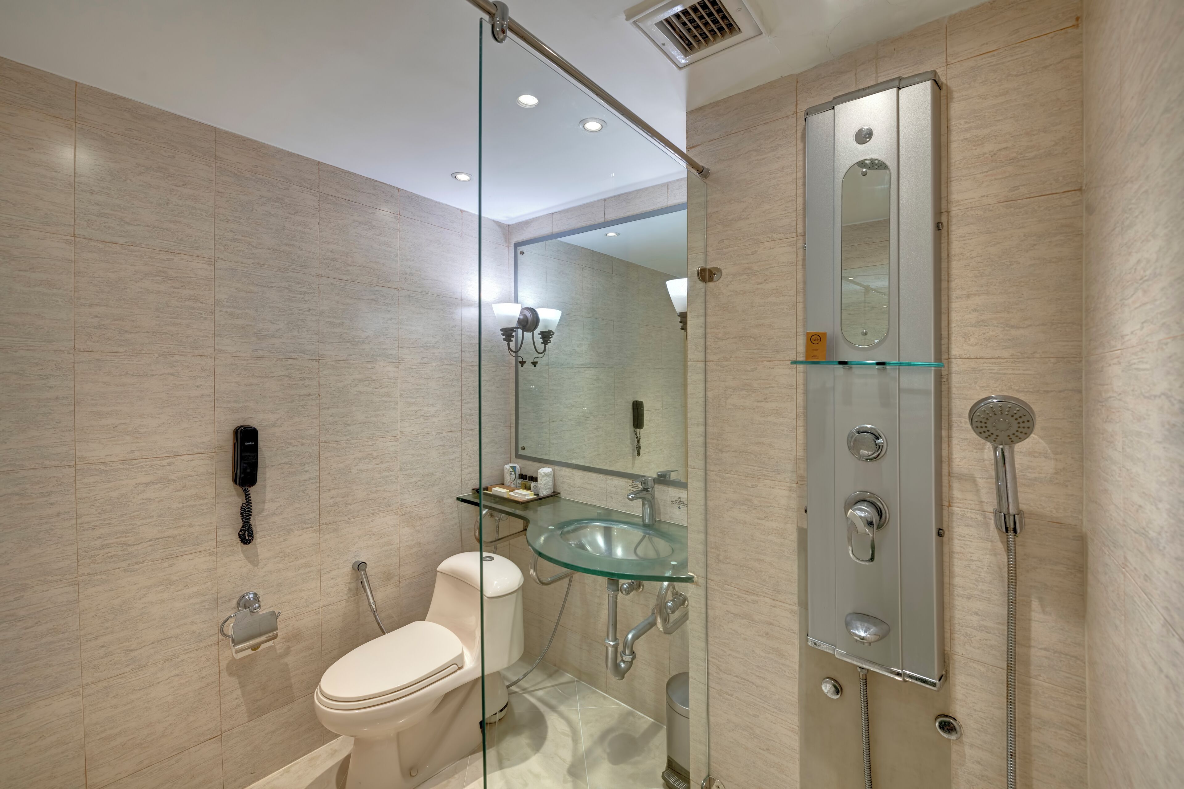 Een moderne badkamer met een douchecabine van glas, een glazen wastafel en een toilet.
