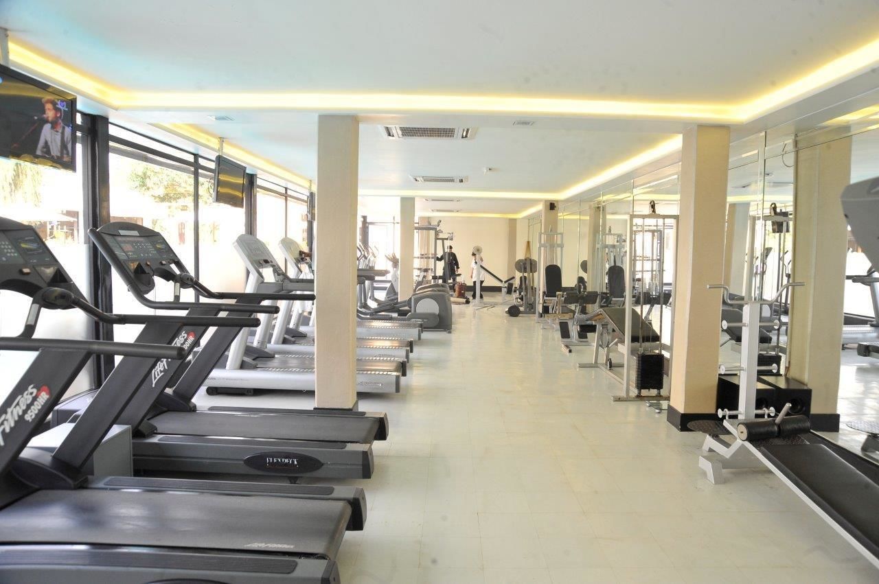 Un gimnasio con cintas de correr, máquinas de pesas y espejos.