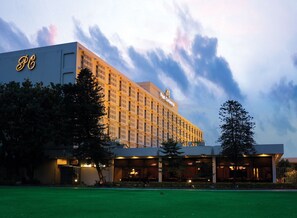 A large hotel with a modern facade, multiple balconies, and a well-maintained lawn.