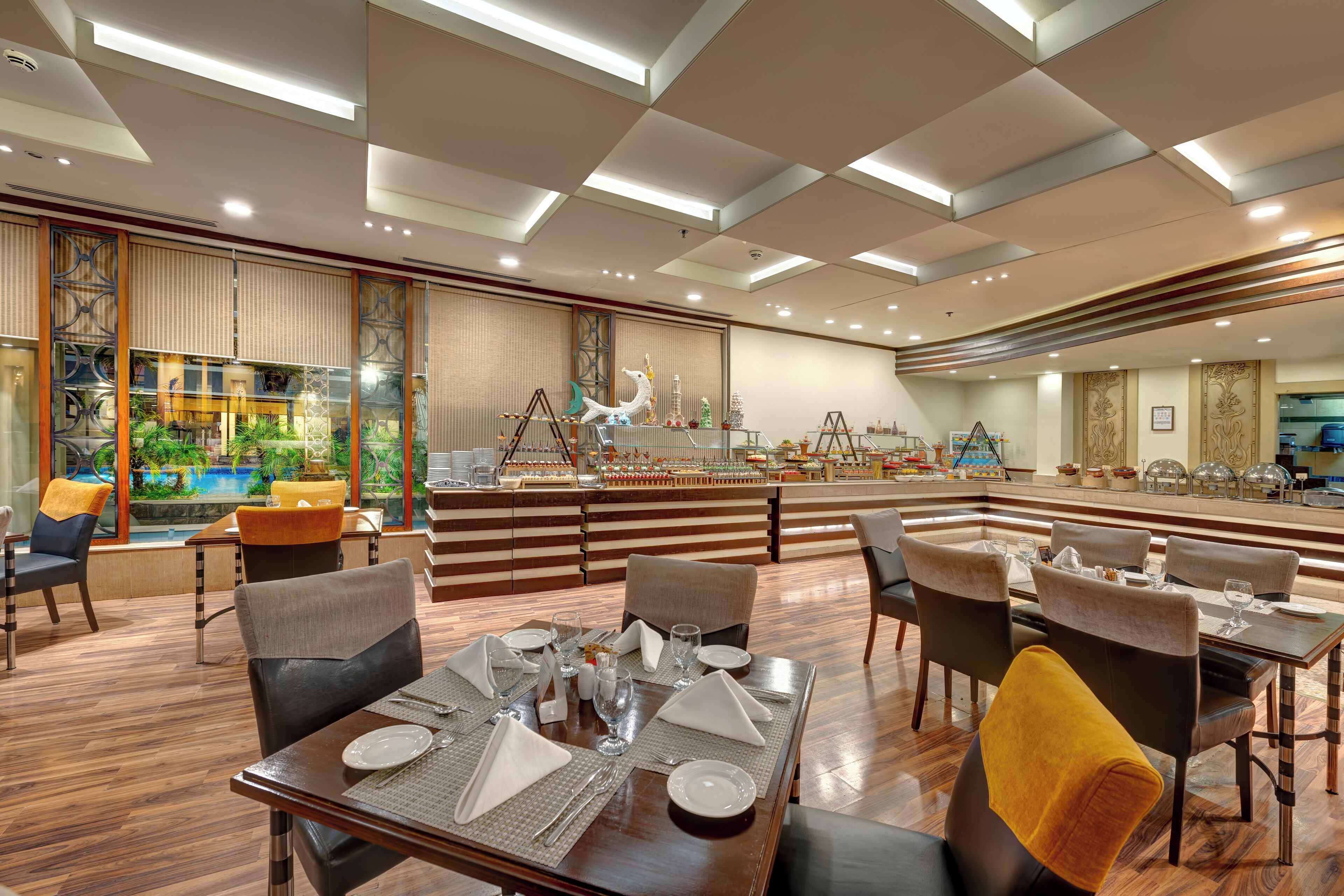 Un restaurante espacioso con techos altos, iluminación moderna y vistas a una piscina.
