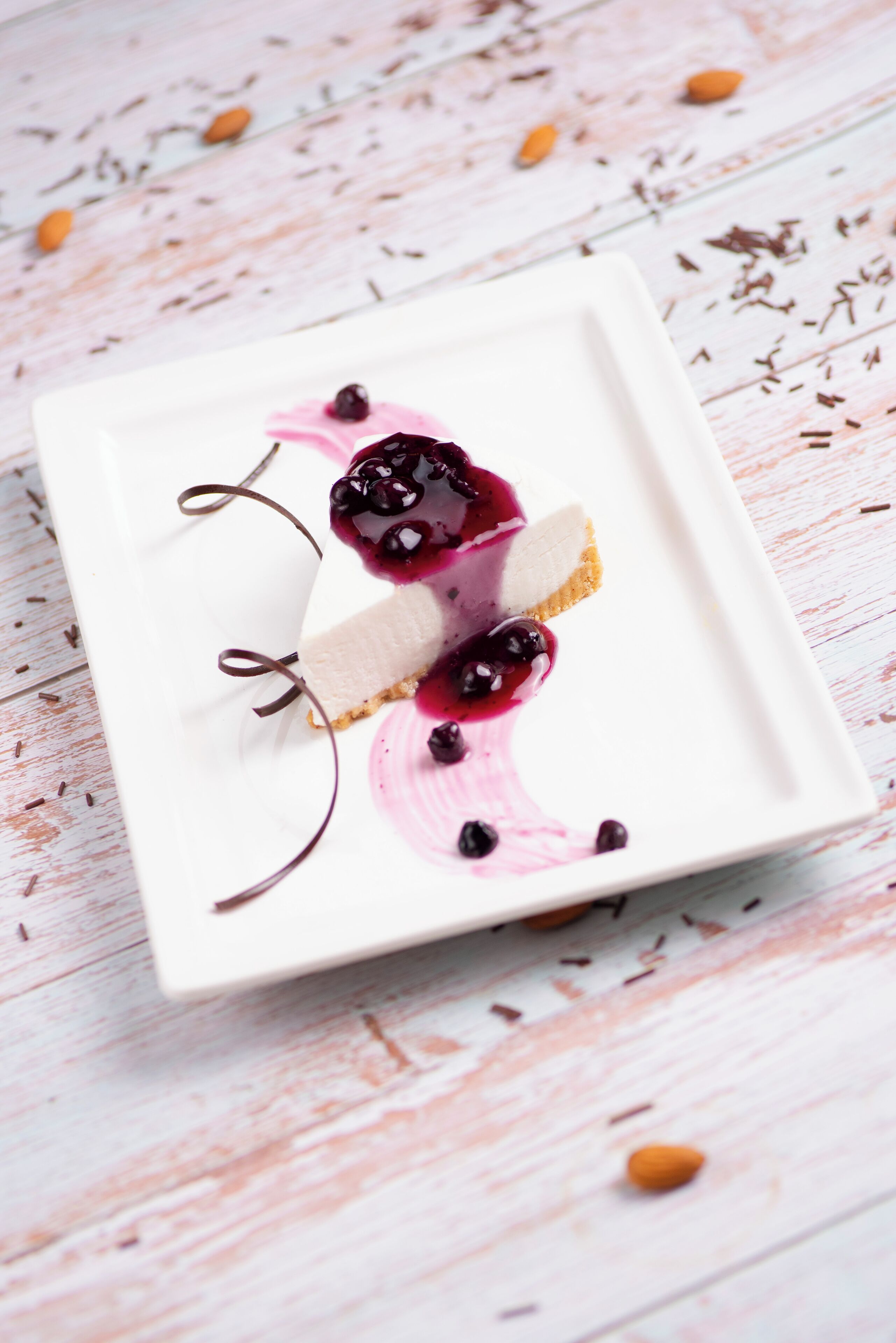 Een wit, vierkant bord met dessert op een ruw houten oppervlak.