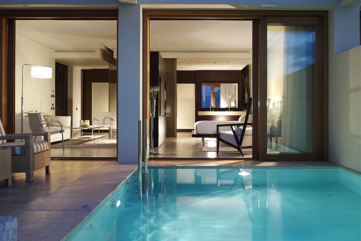 Ein moderner Poolbereich mit klarem Pool, Liegestühlen und einem gut beleuchteten Innenraum.