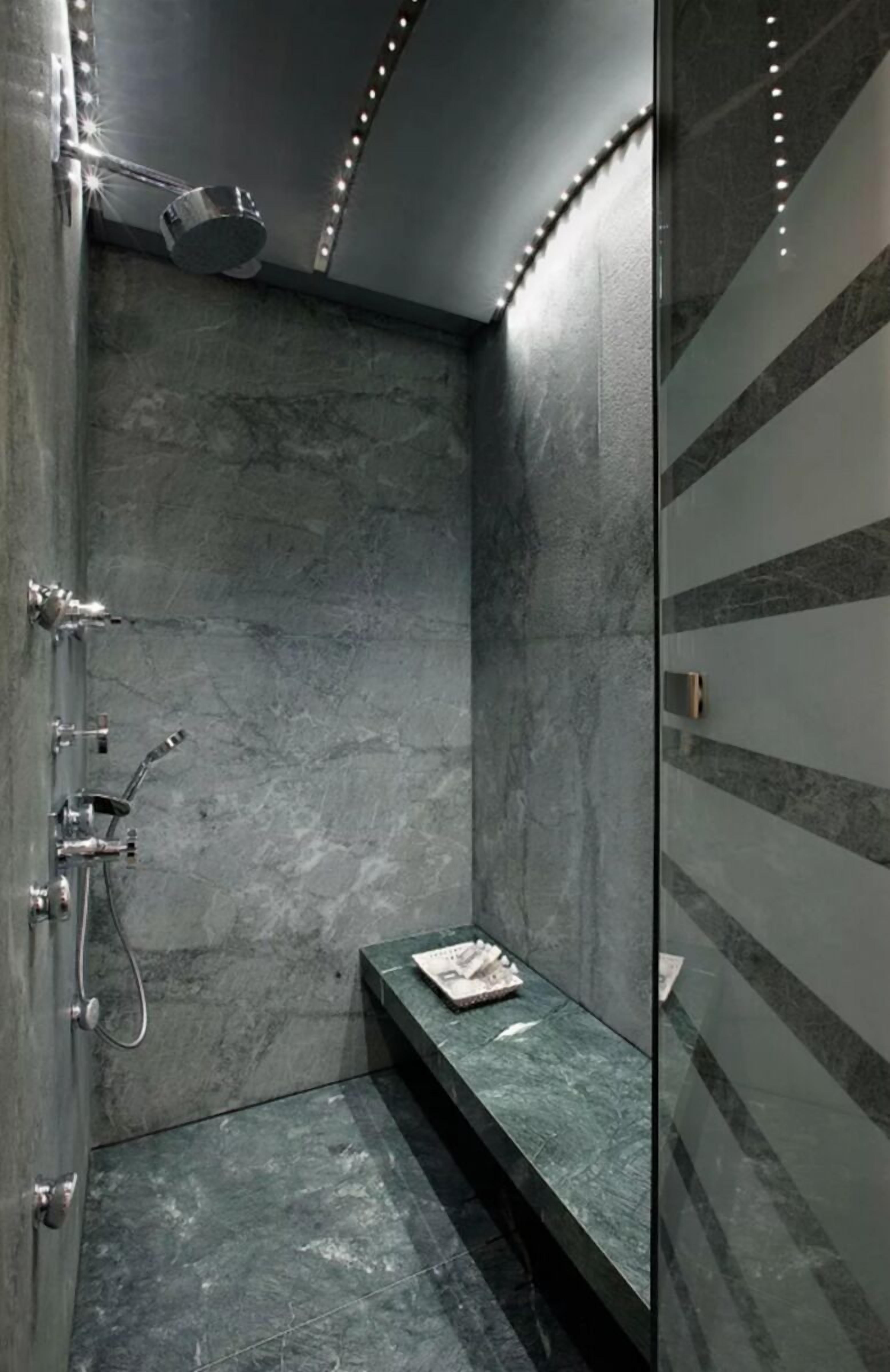 Ein modernes Badezimmer mit Dusche, Sitzbank und Spiegel.