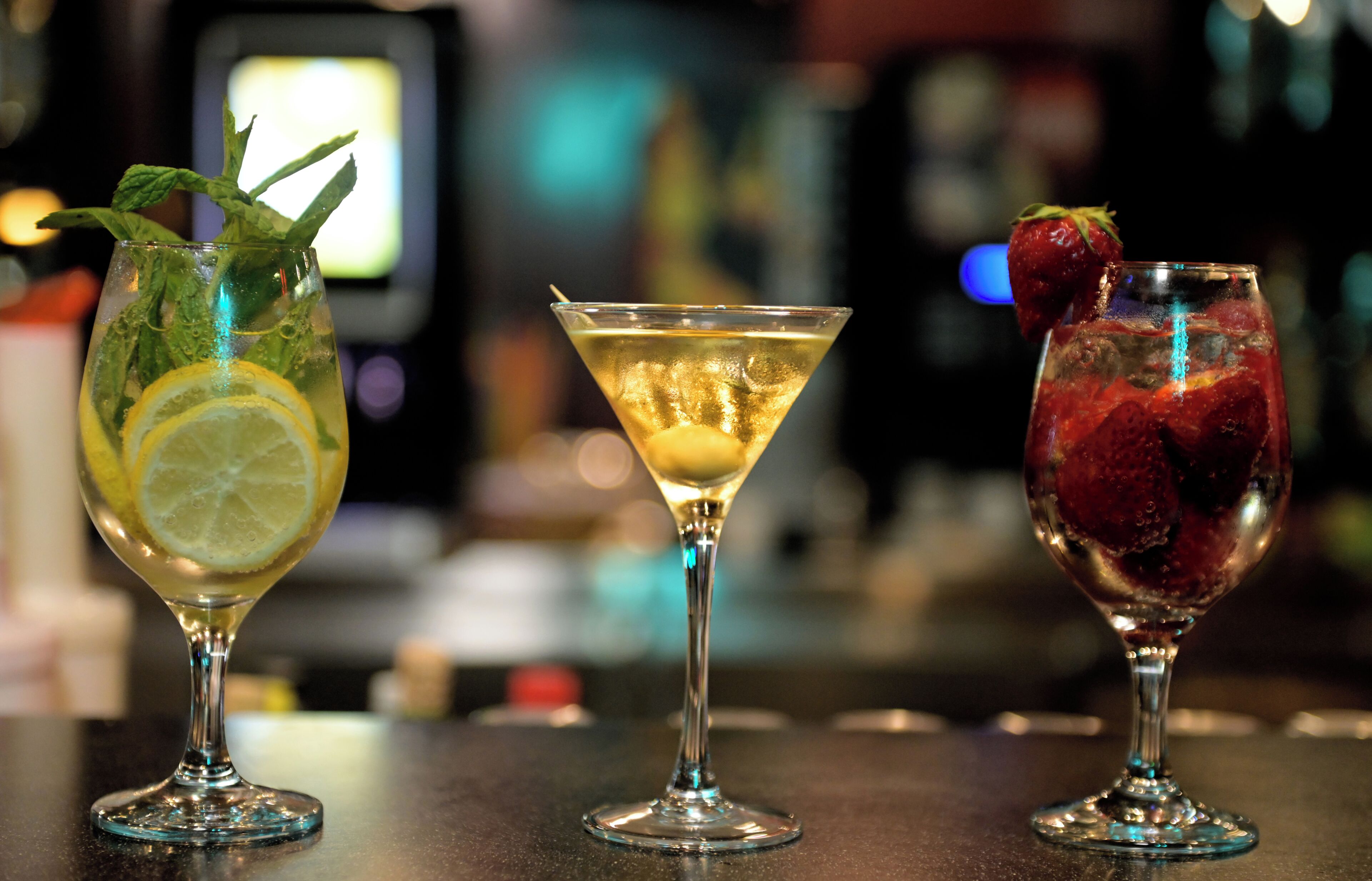 Drei Cocktails auf einer Bar, unscharfer Hintergrund.