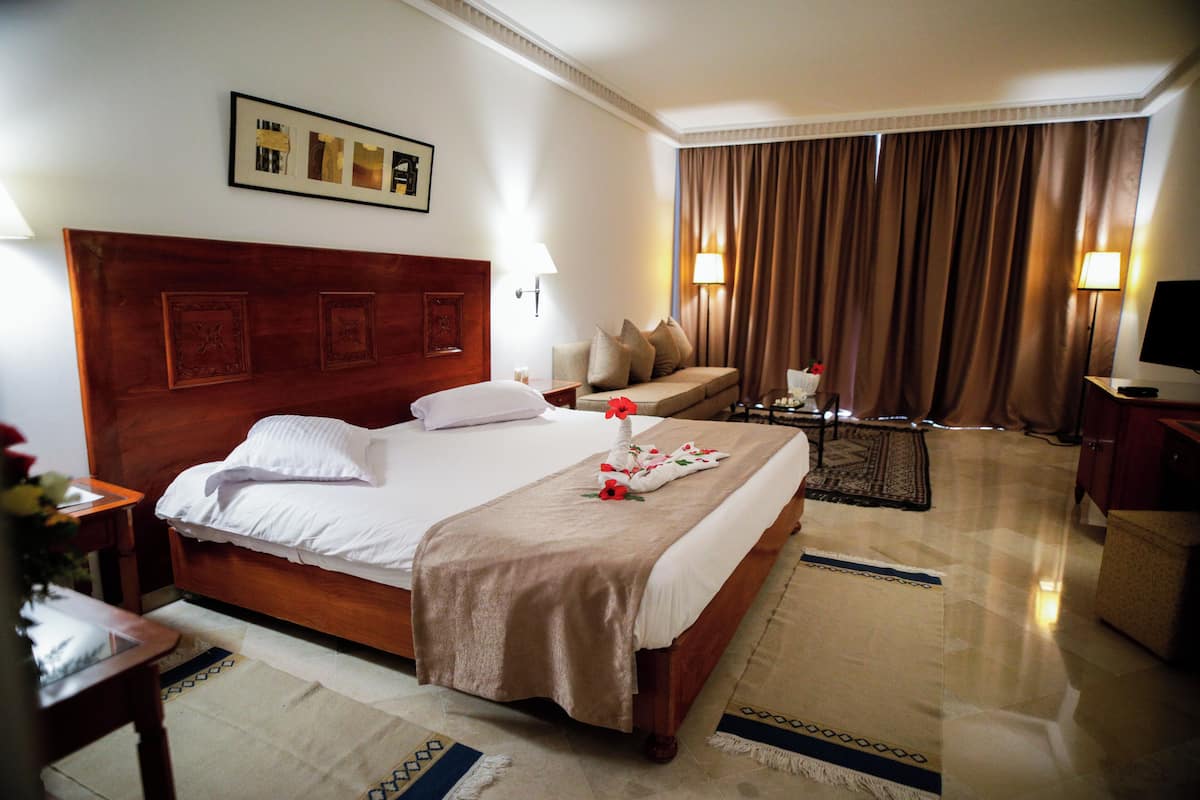 Une chambre d’hôtel avec un grand lit, un canapé, une table basse et un téléviseur.