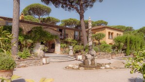 A courtyard with a fountain, stone steps, and a building with balconies. - Hôtel Villa Marie St Tropez (Ramatuelle)