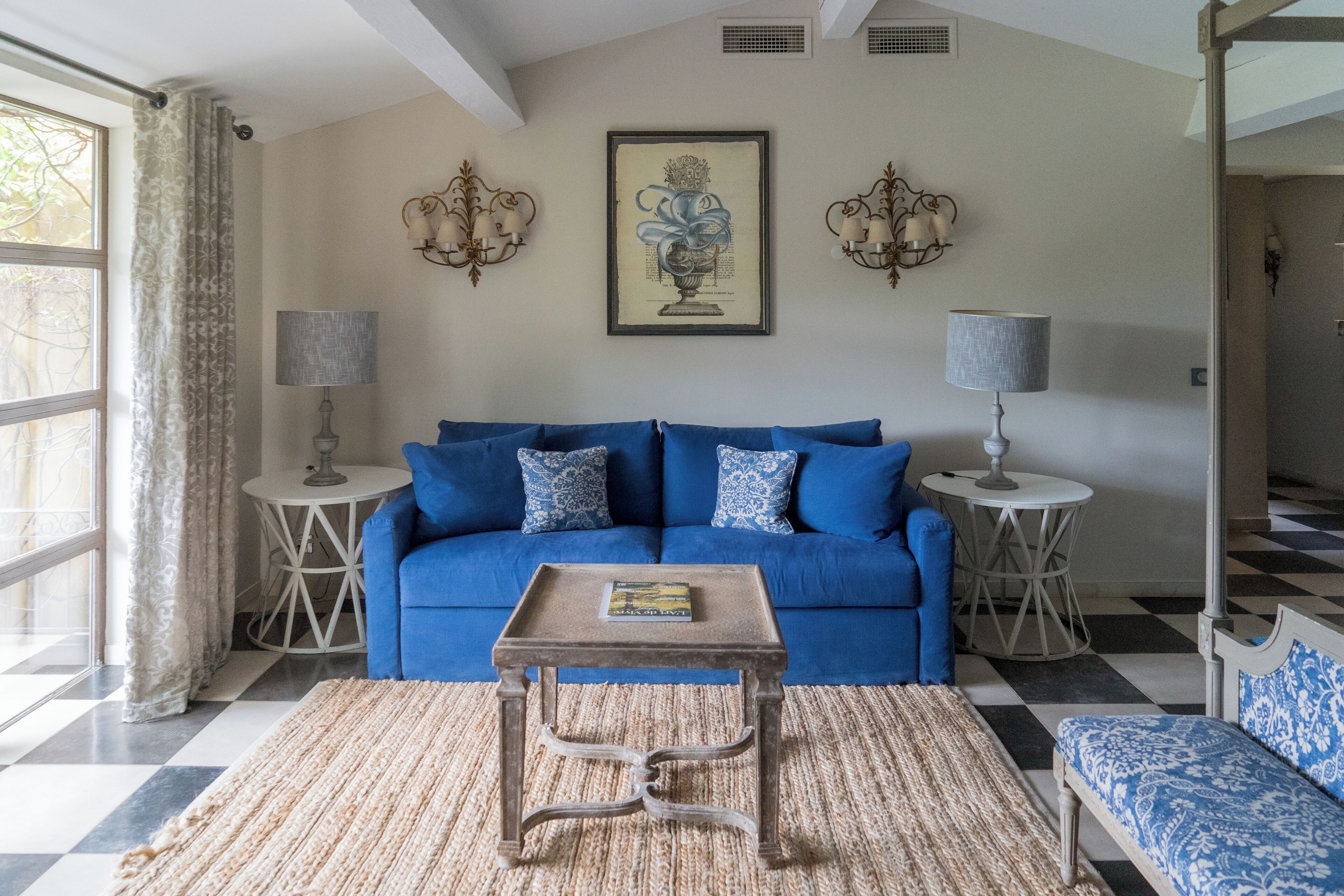 A living room with a blue sofa, a small wooden table, and two wall-mounted lamps.