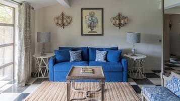 A living room with a blue sofa, a small wooden table, and two wall-mounted lamps.