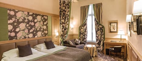 A hotel room with a large bed, a desk, a chair, and a small table.