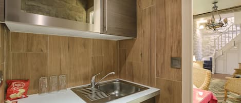 Una cocina con campana de acero inoxidable, armarios de madera y encimera blanca.