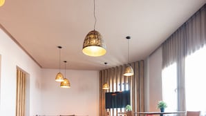 A modern living room with a sofa, dining table, chairs, and pendant lights. - Hotel ibis El Jadida (El Jadida)