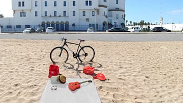 Une plage avec un sable blanc, un vélo et une guitare posés sur le sable.