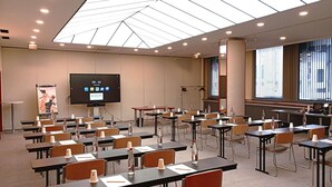 A conference room with tables, chairs, a large screen, and a poster. - Hôtel Mercure Limoges Centre (Limoges)