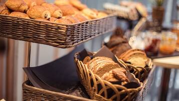 A breakfast buffet with various breads and pastries.