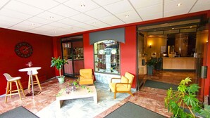 A lobby with red walls, a clock, a reception desk, and seating areas. - Hôtel Mercure Limoges Centre (Limoges)