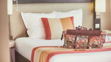 Un lit bien fait, avec un sac à motifs et des lunettes posés dessus.