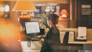 A person working at a desk with a computer, a lamp, and a printer in a warmly lit room. - Hôtel Mercure Limoges Centre (Limoges)