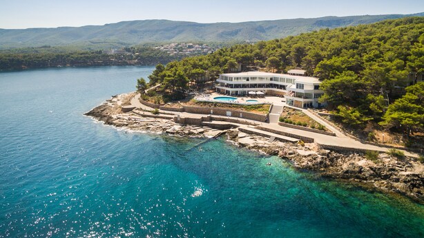 A coastal property with a swimming pool, a large building, and a view of the sea and hills. - Resort Fontana (Jelsa)