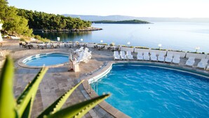 A pool area with two separate pools, lounge chairs, and a view of the lake. - Resort Fontana (Jelsa)