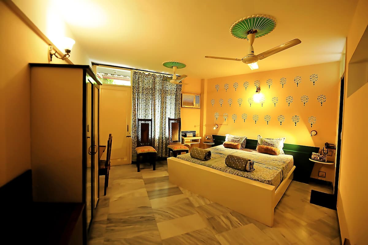 A bedroom with a bed, a ceiling fan, a desk, and a chair.