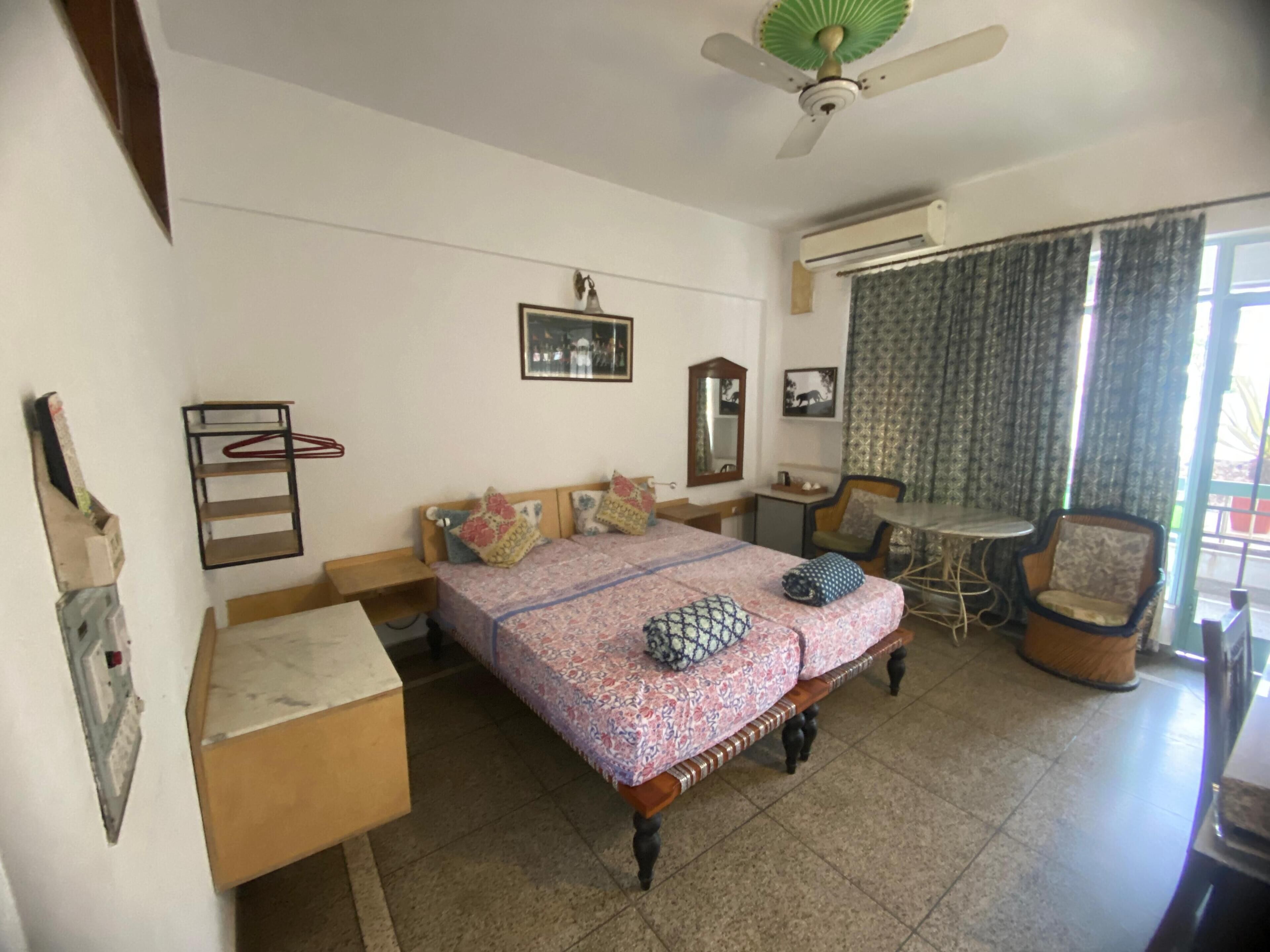 A bedroom with a bed, bedside tables, a chair, a small table, and a ceiling fan.