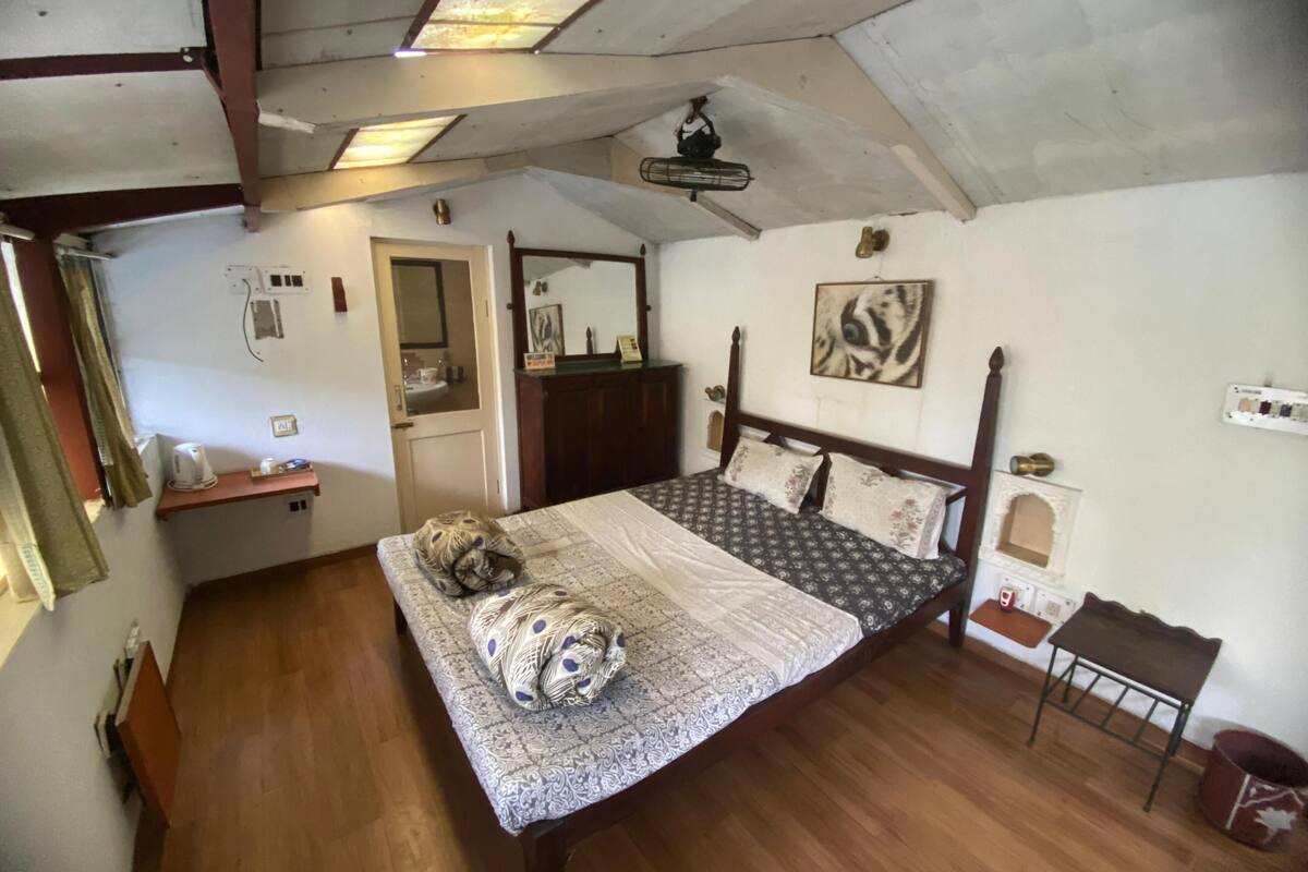 A bedroom with a wooden bed, a mirror, a small table, and a ceiling fan.