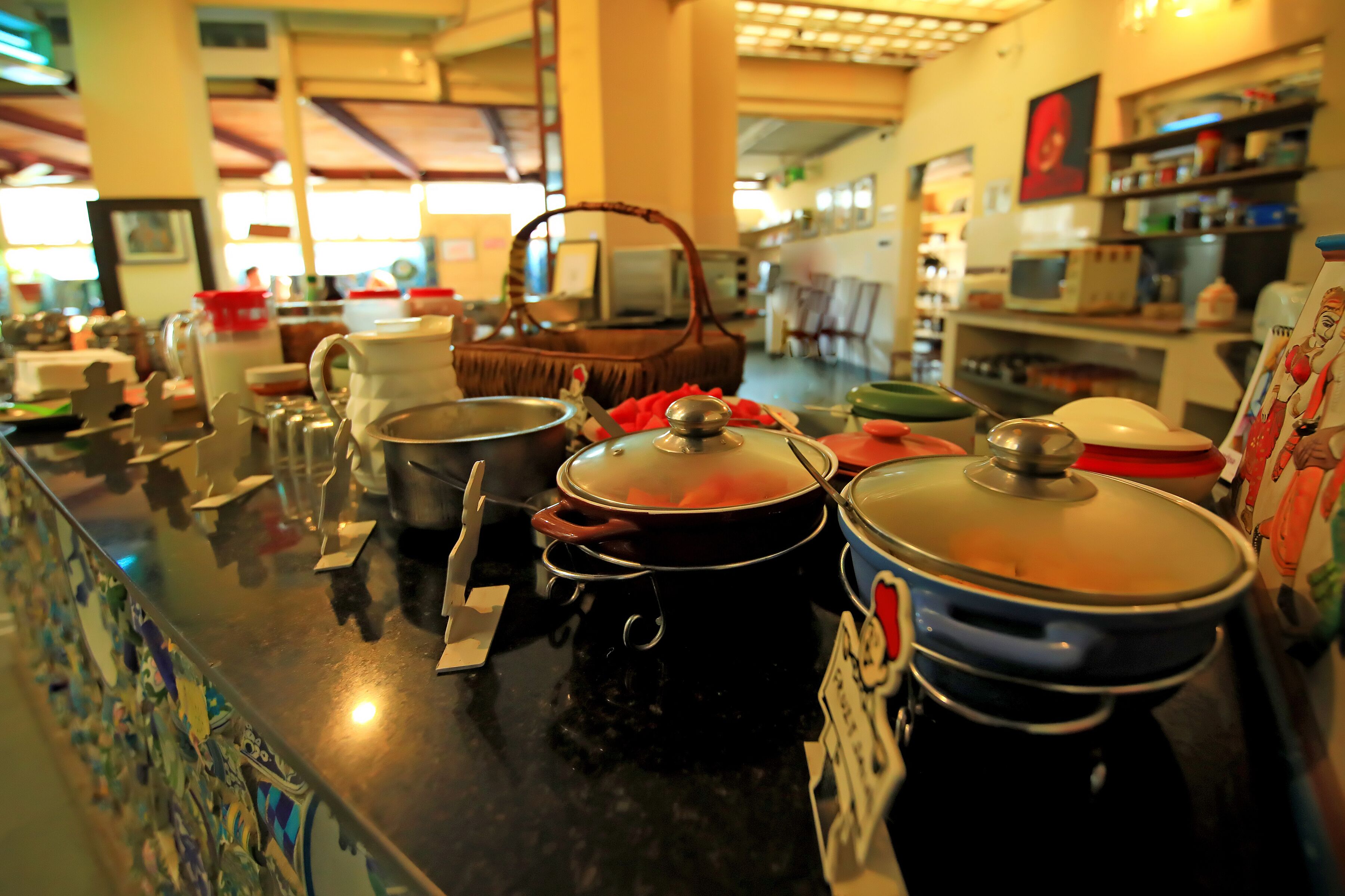 Zona de bufé con varios recipientes de comida y utensilios sobre una encimera.