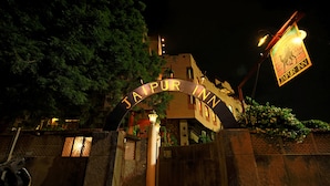 Indgangen til Jaipur Inn med et skilt over porten og en lygtepæl til højre.