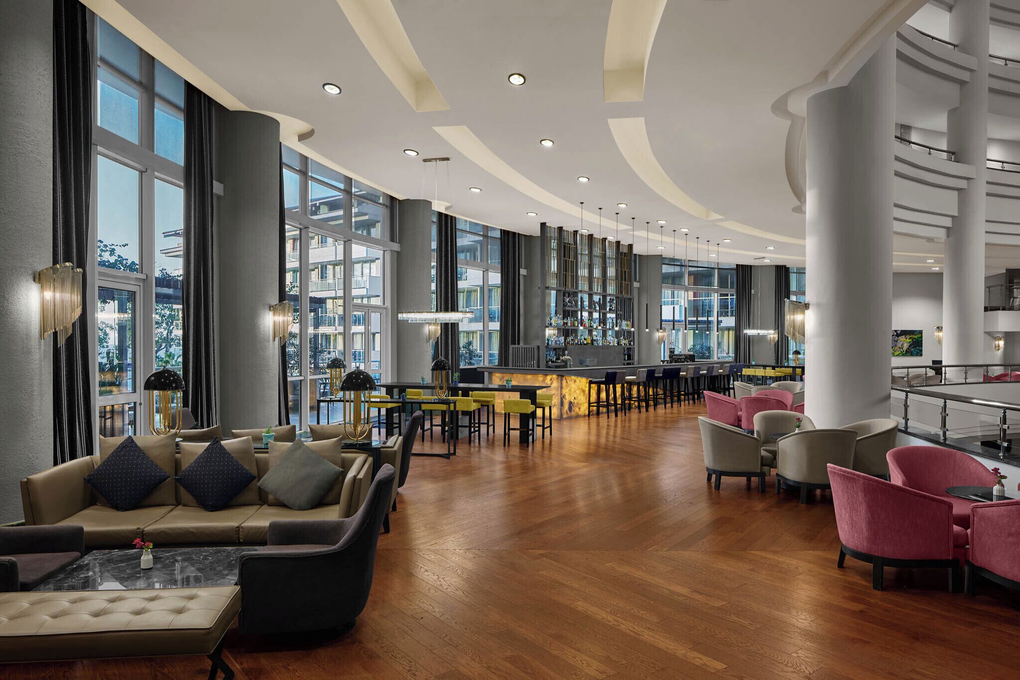 Un vestíbulo amplio con zona de bar, asientos y grandes ventanales con vistas a la ciudad.