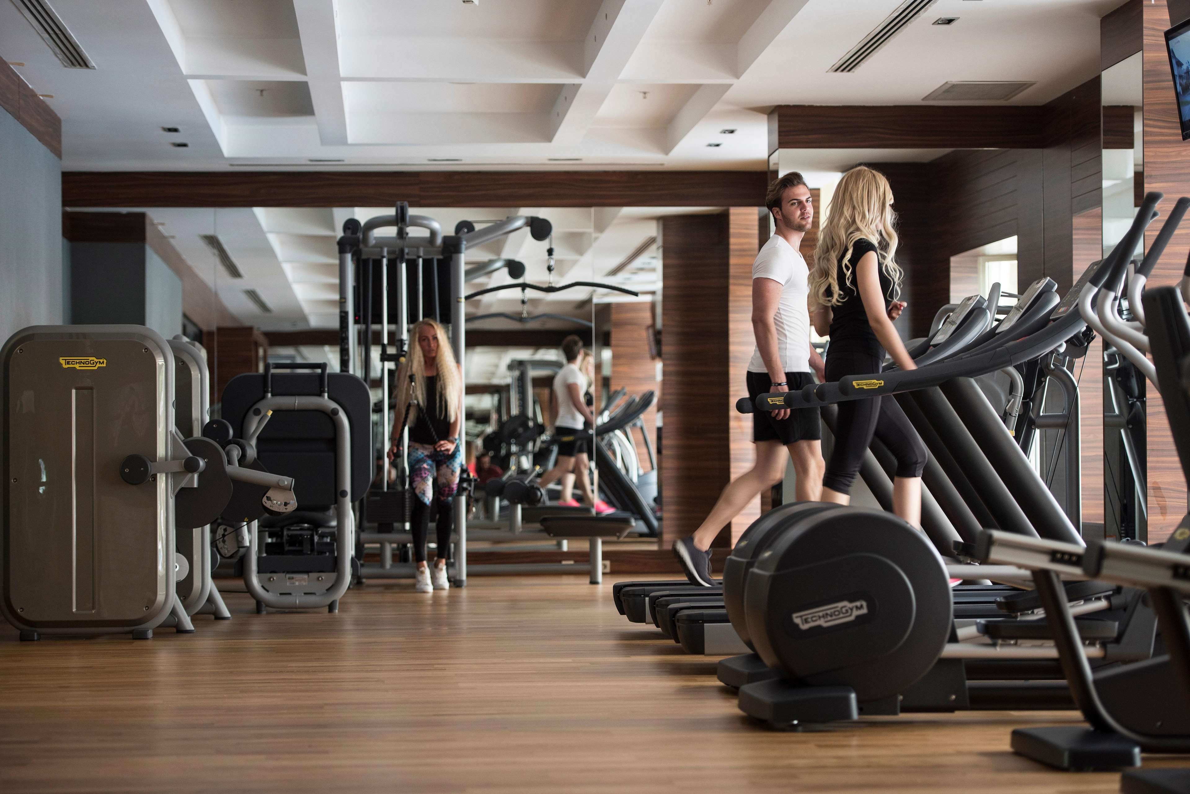 A gym with treadmills, weight machines, and a mirrored wall.
