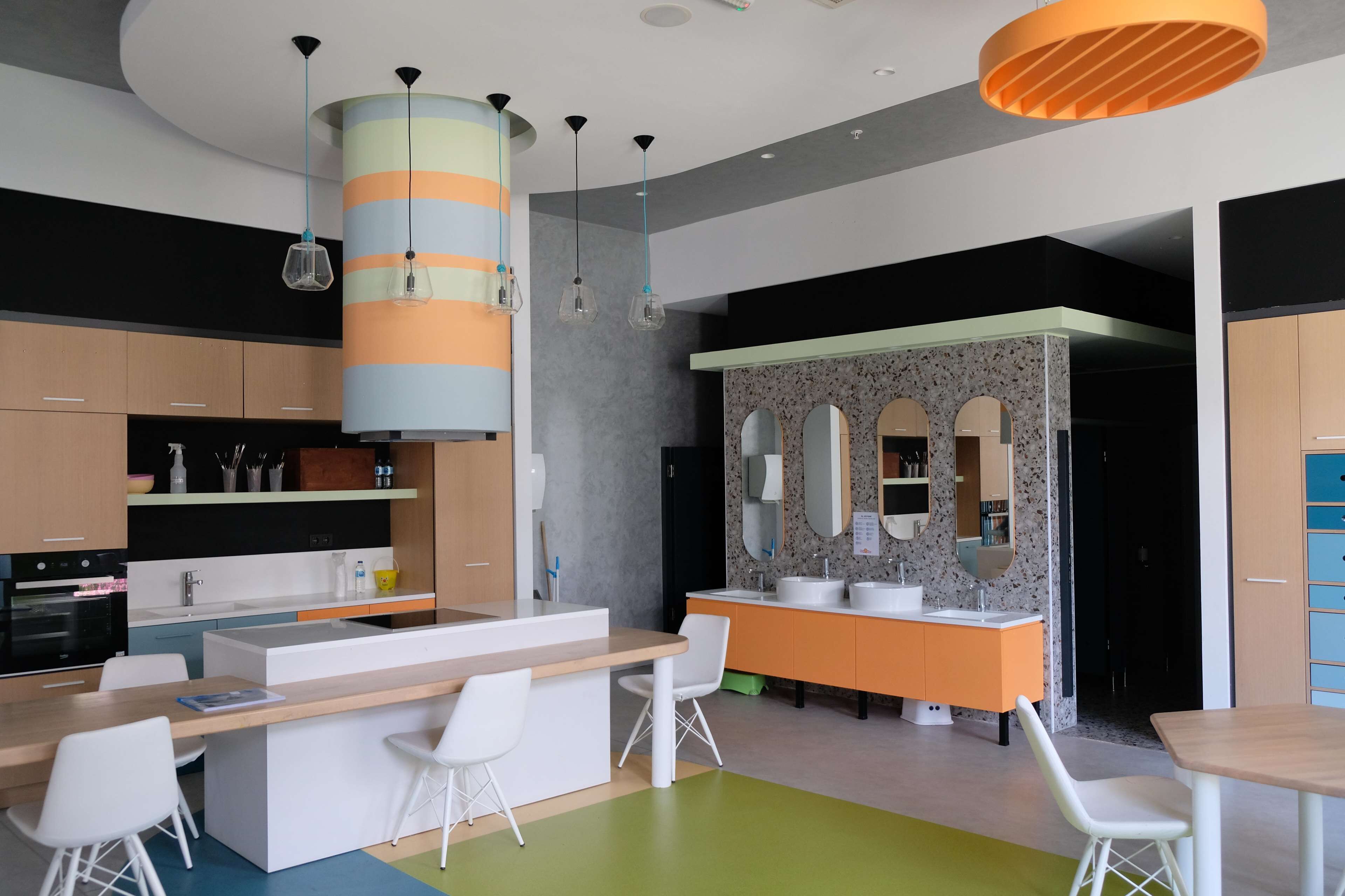 Una cucina moderna con isola centrale, sgabelli da bar bianchi e una barra arancione e bianca integrata.