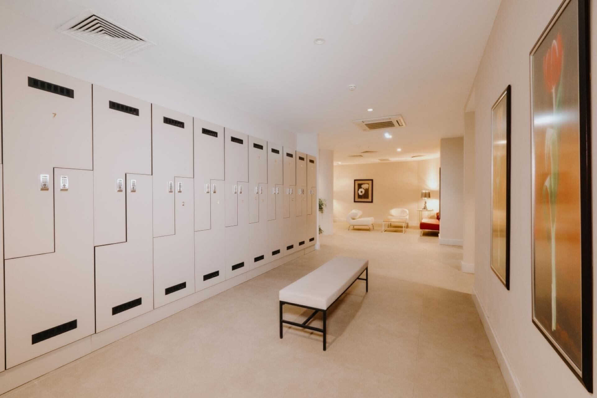 A locker room with multiple lockers, a bench, and a framed picture on the wall.