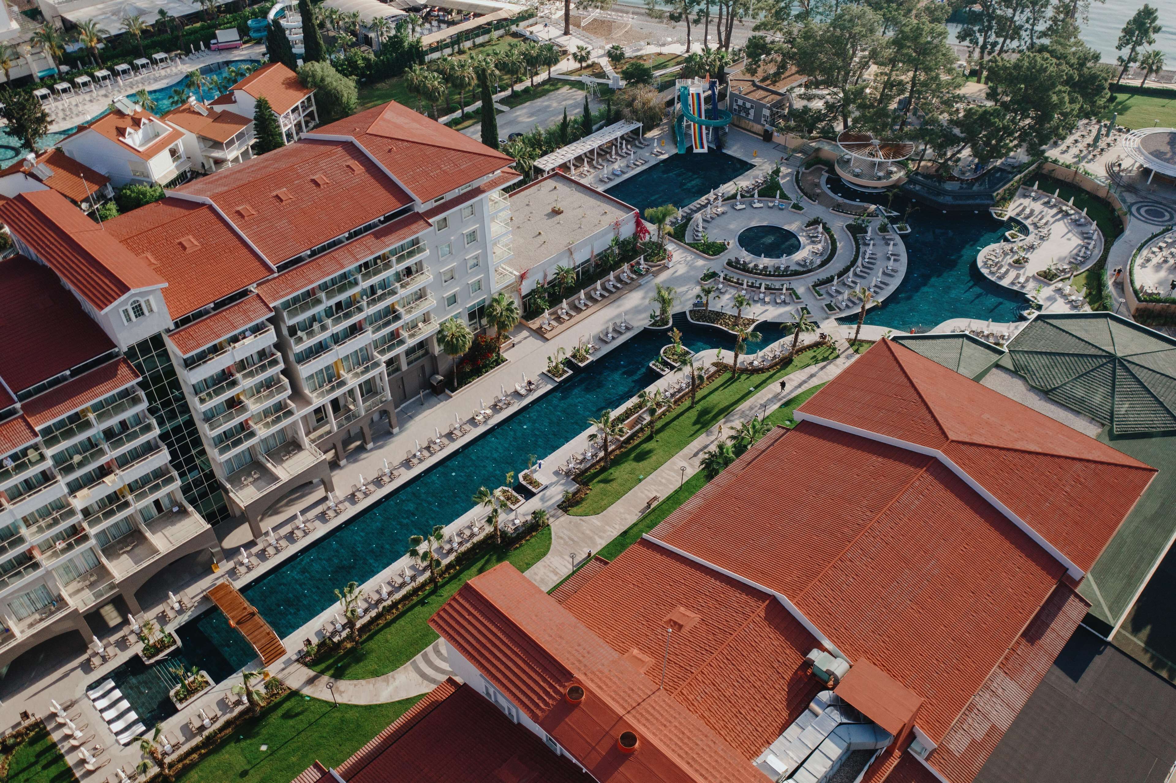 Un hotel con varias piscinas, una fuente central y una terraza en la azotea.