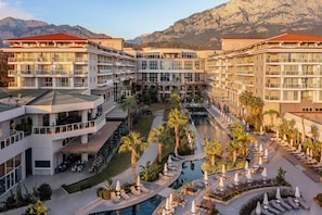 A hotel with multiple floors, outdoor pools, and a central courtyard with palm trees.