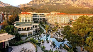 Ett hotell med flera byggnader, en swimmingpool och en bergig bakgrund.