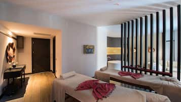 Habitación de hotel con dos camas, zona de estar, escritorio y un ventanal grande con persianas.