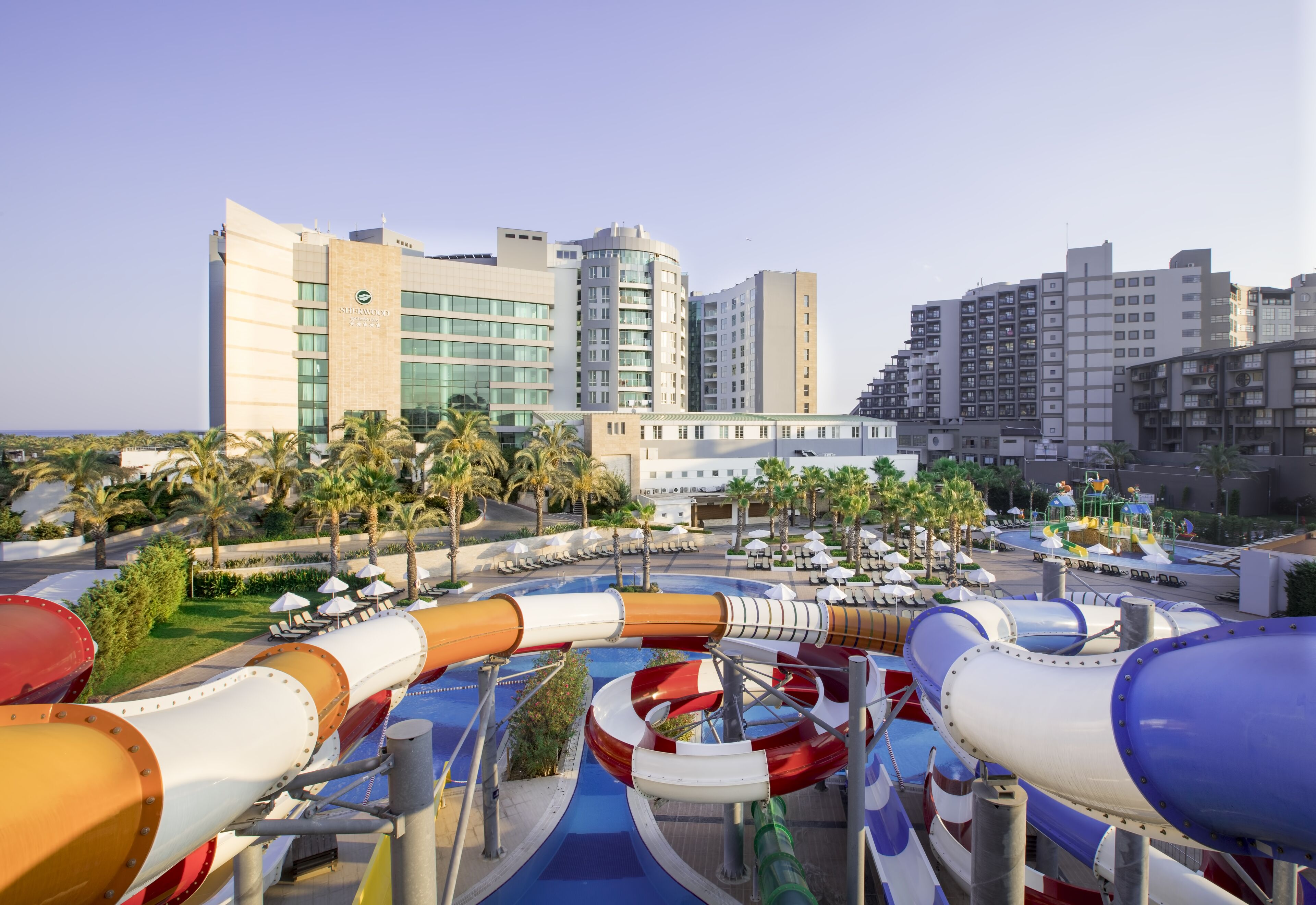 A water park with multiple slides and a hotel in the background.
