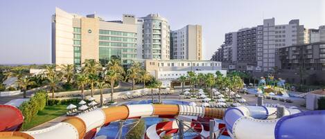 A water park with multiple slides and a hotel in the background.