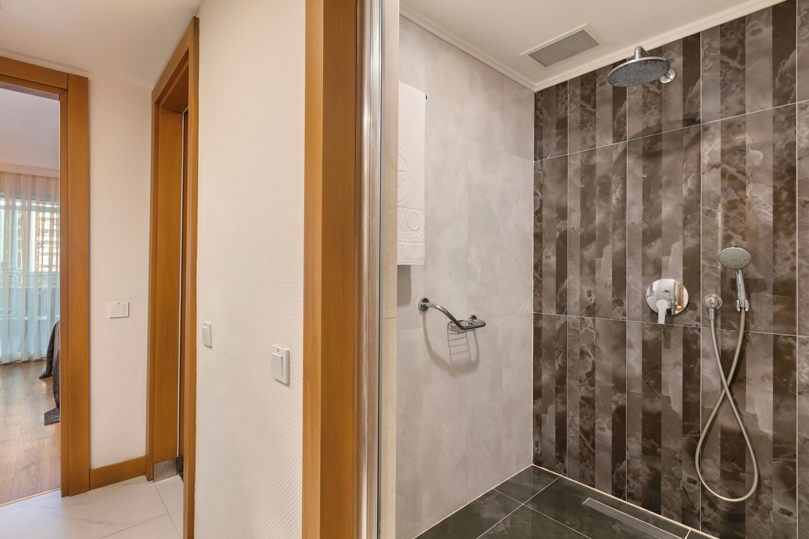 Un baño moderno con cabina de ducha de vidrio, un cabezal de ducha de mano y un grifo empotrado.