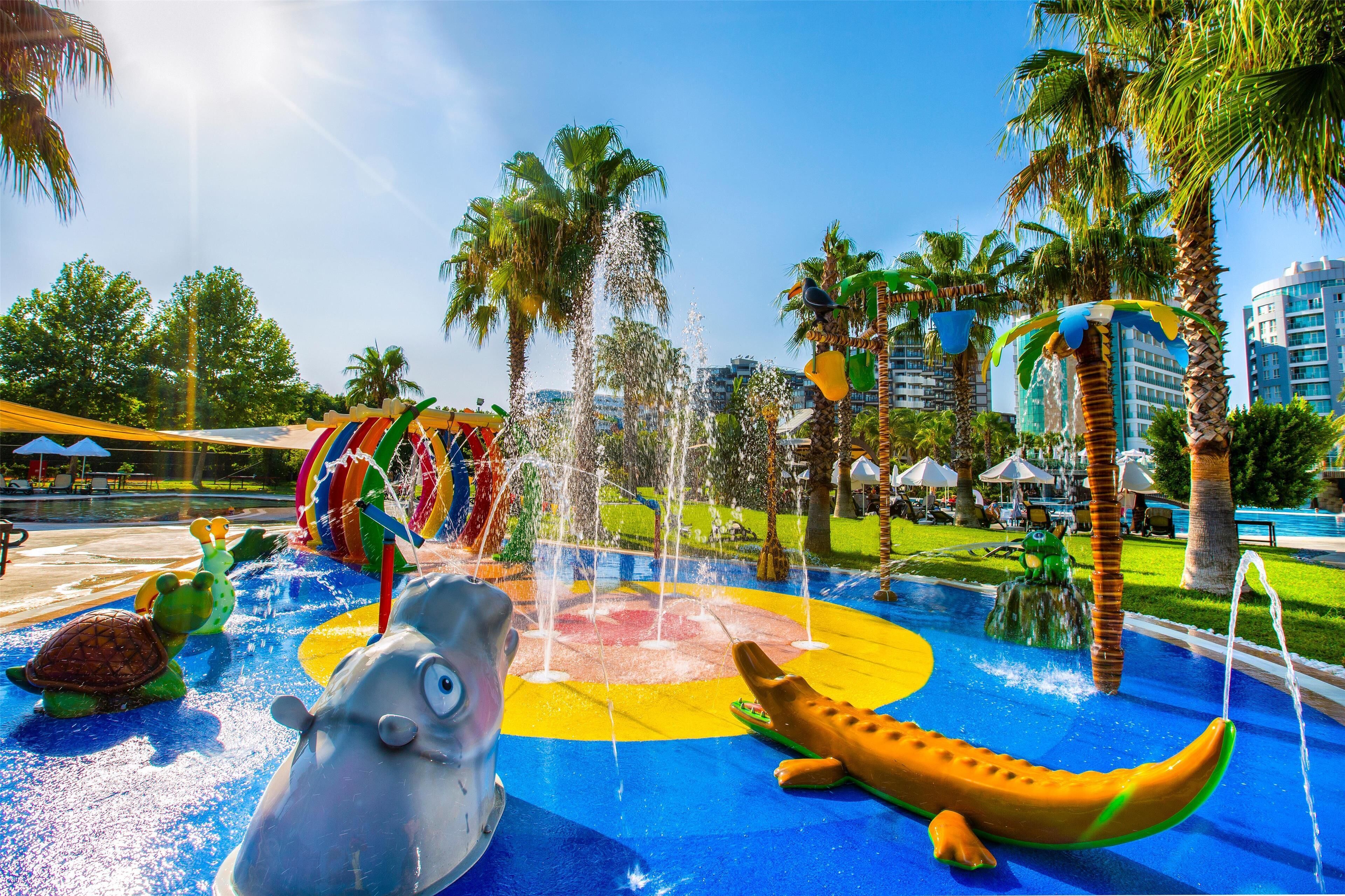 Un parque acuático con un área de juegos colorida, que incluye un tobogán y diversas atracciones acuáticas.