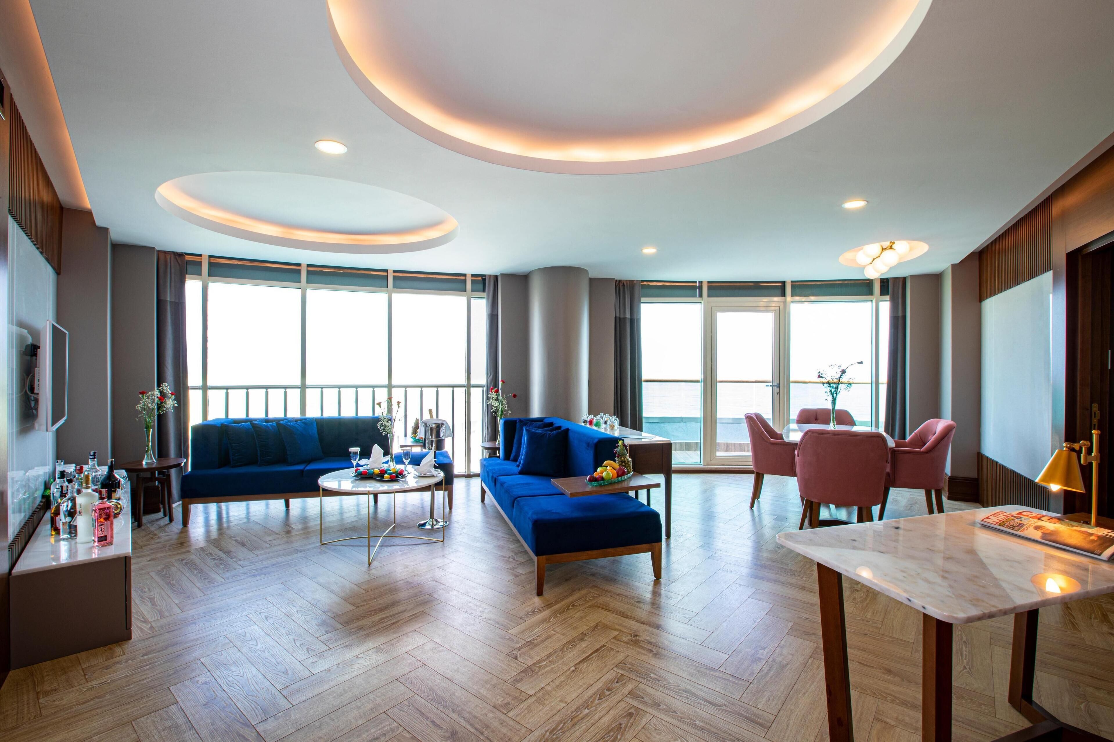 Un salon moderne avec un canapé bleu, une table basse en bois et un coin repas avec des chaises roses.