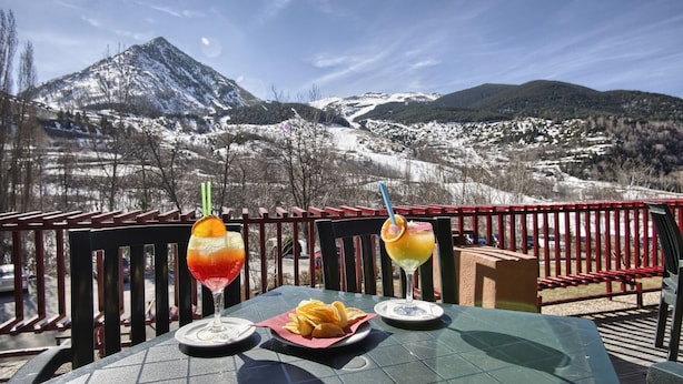 Une table avec deux boissons et une assiette de frites, le tout placé devant un paysage de montagne.
