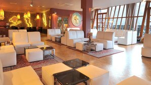 Un hall d’entrée spacieux, doté de canapés blancs, d’une table basse et d’une grande fenêtre offrant une vue sur l’extérieur.
