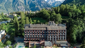 Un hôtel à plusieurs étages doté d’une cour intérieure, entouré d’une végétation luxuriante et avec des montagnes en toile de fond.