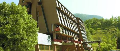A modern building with a unique architectural design, featuring a large balcony and a swimming pool area.
