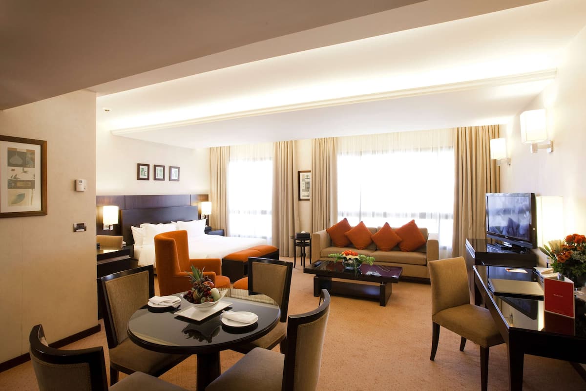 Ein Hotelzimmer mit Bett, Sofa, Esstisch und Fernseher.