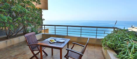 A balcony with a table and chairs, overlooking a body of water.