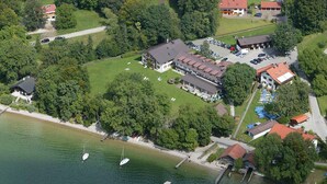 Luchtbeeld van een kustbezit met meerdere gebouwen, een jachthaven met diverse boten en weelderige begroeiing rondom.