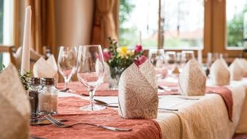 A table set for a meal with a red tablecloth, salt and pepper shakers, a candle, and a patterned napkin holder.